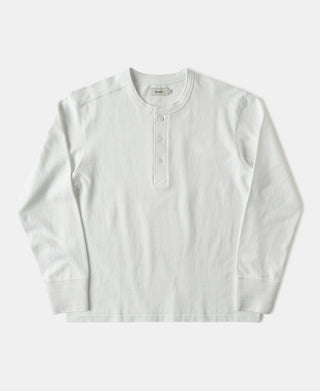 A long-sleeve henley shirt in off-white, featuring a three-button placket and ribbed collar, cuffs, and hem, laid flat against a light gray background.