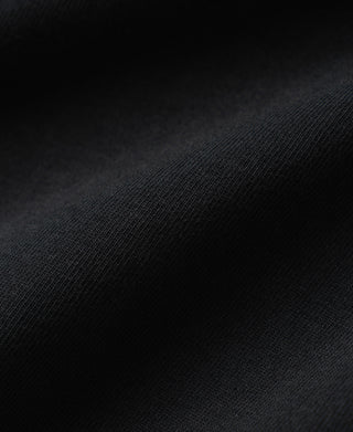 A close-up of dark charcoal gray ribbed knit fabric with soft folds and a fine textured weave.