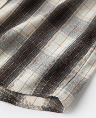 Western plaid shirt hem close-up with cuff and stitched edge, beige and dark stripe plaid.