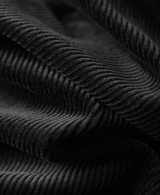 Black corduroy fabric close-up showing ribbed texture lines