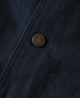 Round metal button on navy cotton canvas jacket front