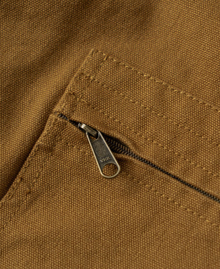 Khaki canvas jacket detail: zipper pull with triangular tab at pocket edge