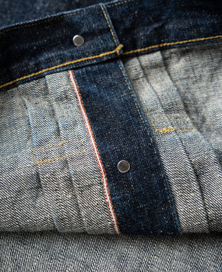Indigo denim jacket placket with snap buttons and contrasting red selvedge strip