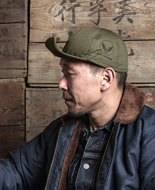 Man wearing an olive A-3 flight cap with Army Air Force emblem