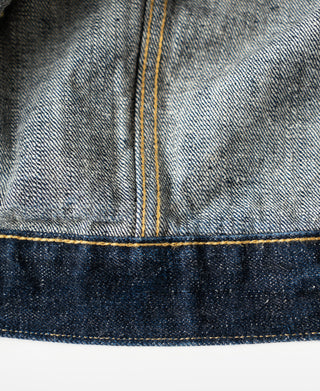 Indigo denim jacket side seam with light chambray lining and yellow stitch