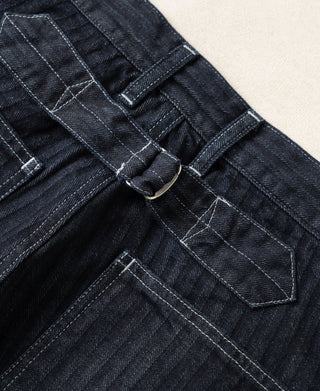 Buckle-back waistband detail on indigo denim fatigue pants with stitched pocket panels