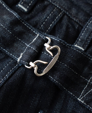 Belt buckle and eyelet closure on indigo denim fatigue pants, stitched waistband tabs