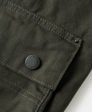Olive canvas jacket cuff with round metal snap button and visible seam stitching
