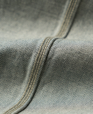 Curved seam and stitching on sage blue denim jacket panel