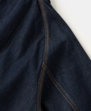 Indigo denim field jacket sleeve seam with contrast orange topstitching.