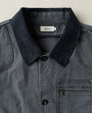 Gray-blue jacket detail showing dark corduroy collar, buttons, and zip chest pocket