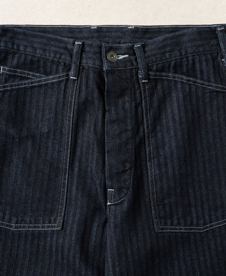 Indigo denim fatigue pants with center front seam and two buttoned pockets