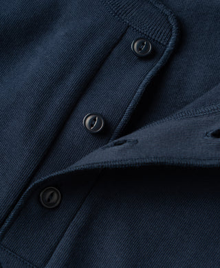 Close-up of a dark navy blue knit garment showing the ribbed collar, buttoned placket, and fabric texture.
