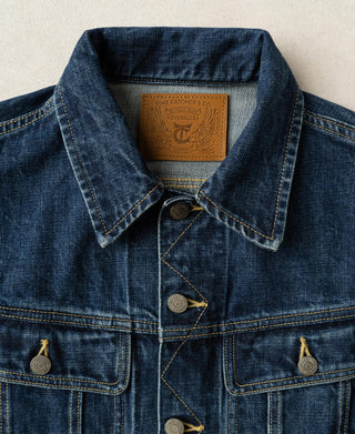 Indigo denim jacket neckline with pointed collar, inner brand tag, and button placket