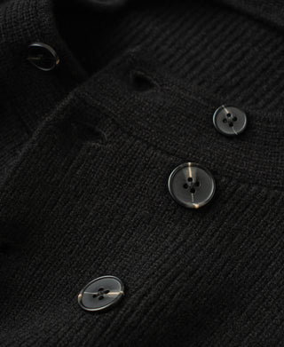 Close-up of black knit cardigan fabric with dark metal button details