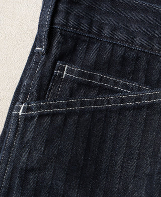 Indigo denim pants showing curved stitched pocket detail and textured fabric weave
