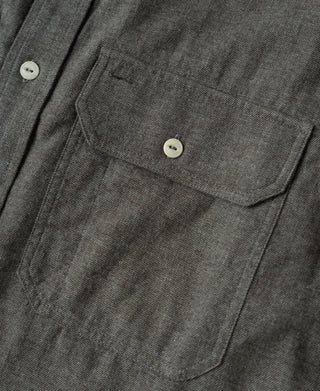 Close-up of dark gray chest pocket and stitched flap detail on work shirt