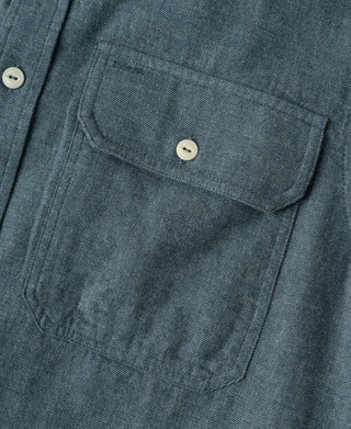 Close-up of blue flannel chest pocket with double-stitched seam and white button.