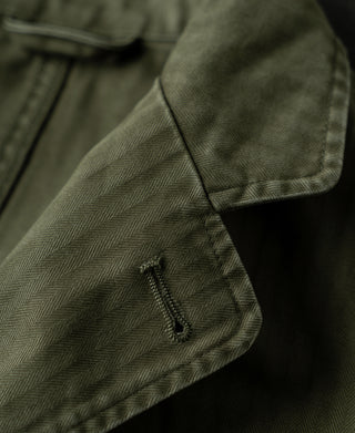 Olive herringbone blazer sleeve cuff with small decorative zipper detail