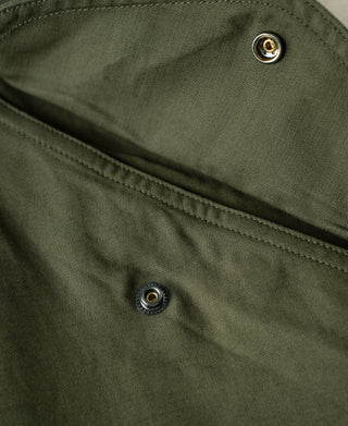 Close-up of olive cargo pocket flap with snap buttons and topstitching