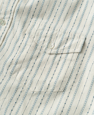 Close-up of chest pocket and button against white fabric with blue jacquard stripes