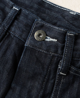 Indigo denim buckle-back fatigue pants with metal button tag and stitched placket