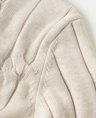 Apricot cable knit sweater shoulder and sleeve with textured cable pattern