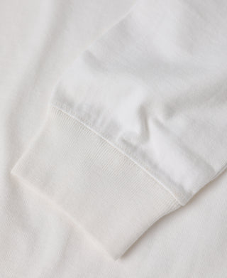 Close-up of a white long-sleeve knit garment showing the sleeve cuff and ribbed fabric texture.