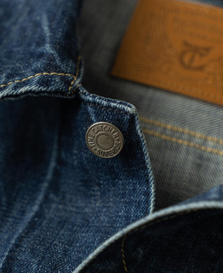 Indigo denim cuff detail with metal button and stitched construction