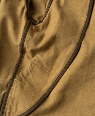 Khaki canvas field jacket close-up showing a curved pocket flap and reinforced stitching.