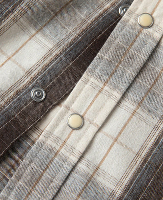 Western plaid shirt detail: snap/metal buttons and front placket on dark beige plaid.