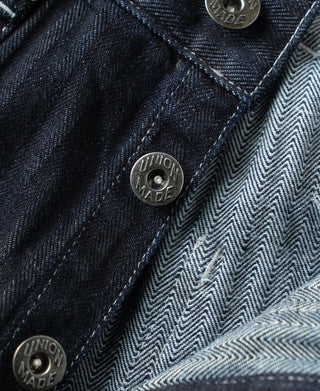 Indigo denim pants with metal buttons and herringbone waistband lining detail