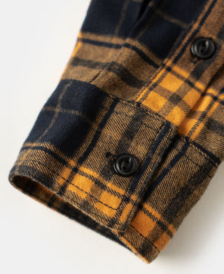Yellow and navy plaid shirt cuff with dark button and stitched hem