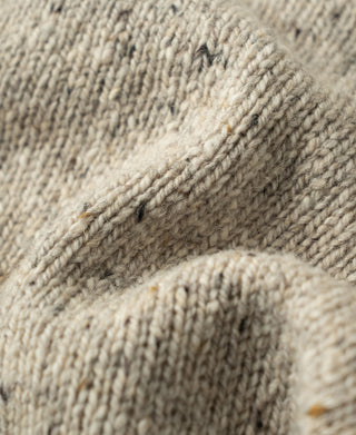 Close-up view of the chunky knit texture and natural speckled wool fibers on an ecru sweater.