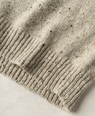 Close-up view of the ribbed hem and heavyweight knit construction on an ecru pure wool sweater.