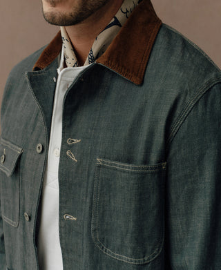 Denim jacket close-up showing brown collar, chest pocket, and hook-and-eye closures