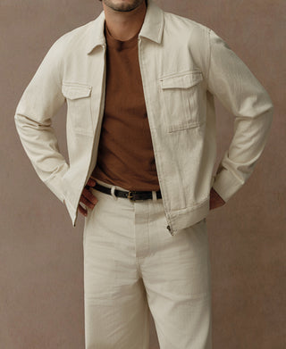 Front view of a natural cotton Eisenhower jacket with two flap chest pockets and zip front.