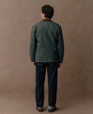 Back view of a sage blue denim jacket with a plain panel and straight hem