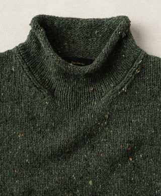 Close-up view of the ribbed roll neck collar on an dark green pure wool fisherman sweater.