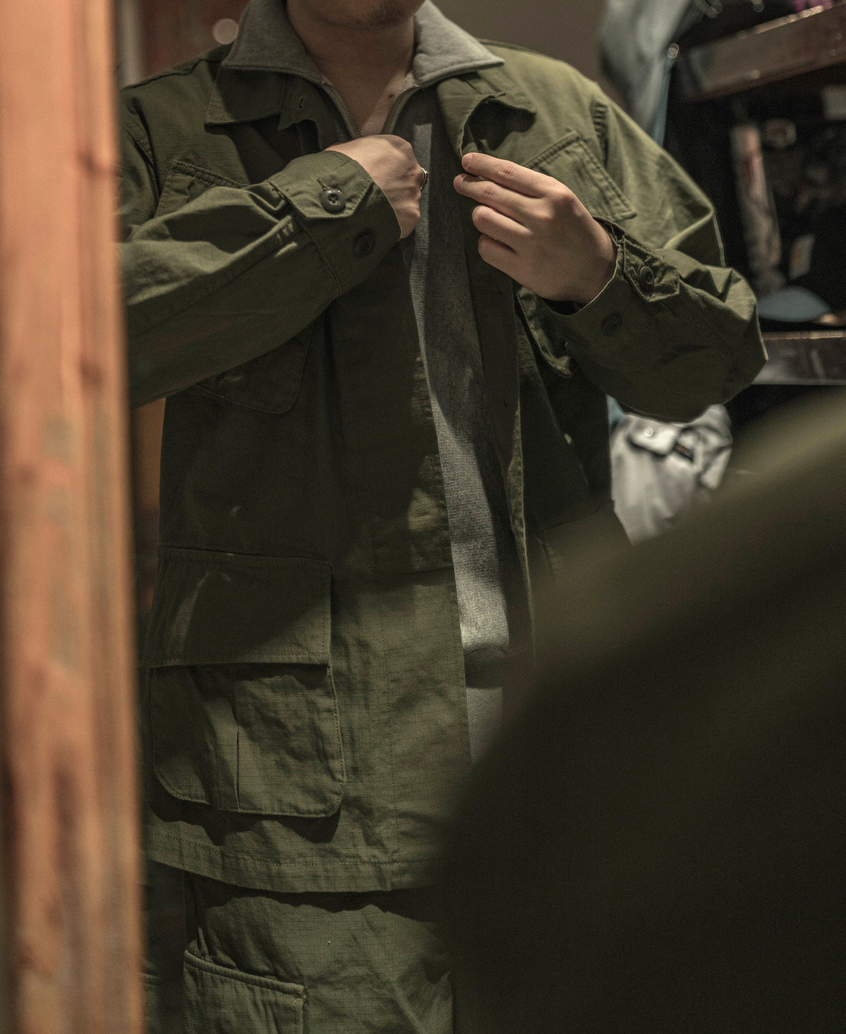 Olive fatigue jacket with flap pockets and button cuffs, worn