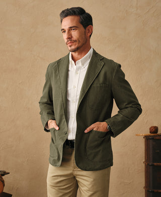 Olive herringbone blazer on model, featuring notch lapel and flap chest pocket