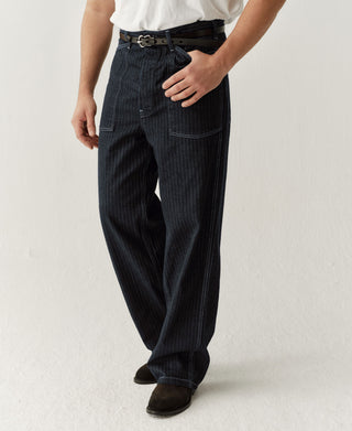 Indigo buckle-back fatigue pants on model, front view with belt loops and cargo pocket