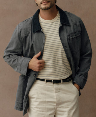 Gray-blue canvas field jacket worn open, showing dark collar and chest pocket